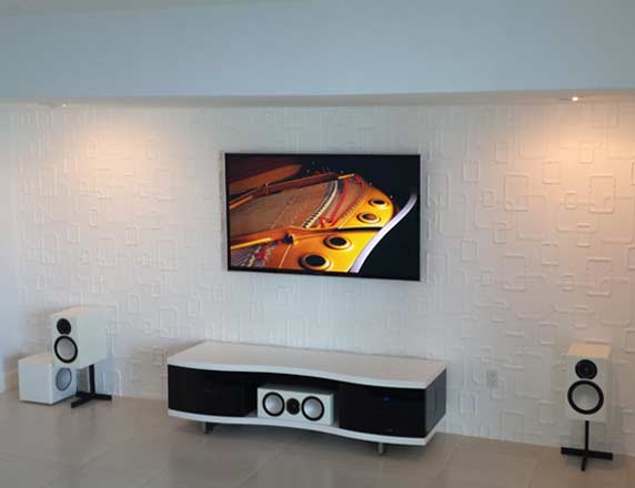 Clean white speaker setup with wall-mounted TV by Entertainment Pros