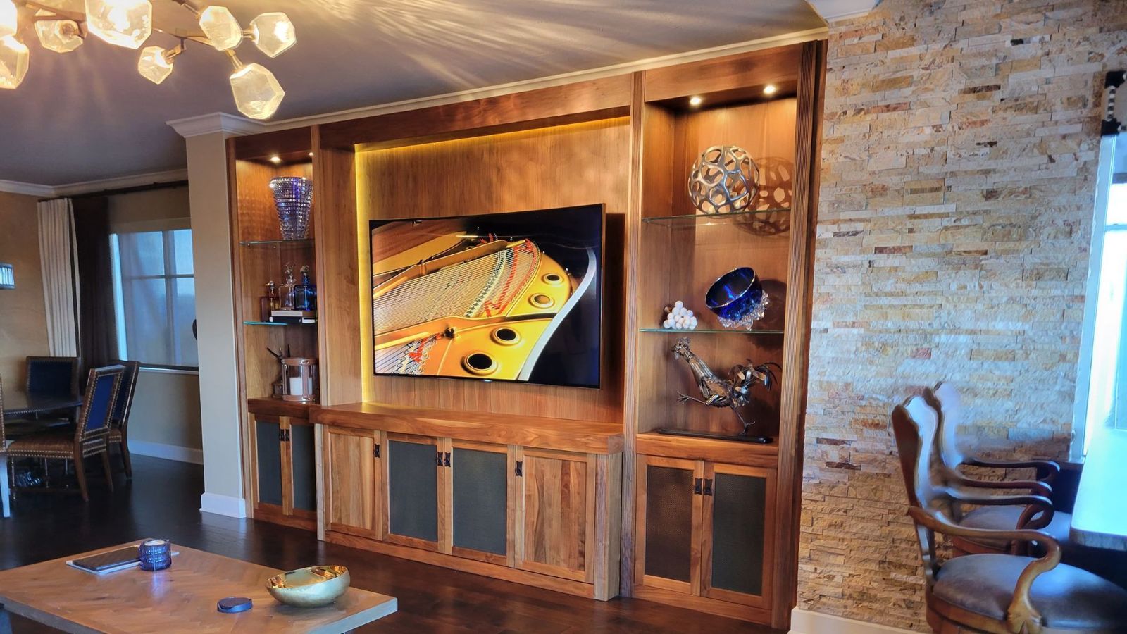 Custom wood entertainment center with mounted TV, LED-backlit shelves and integrated AV equipment