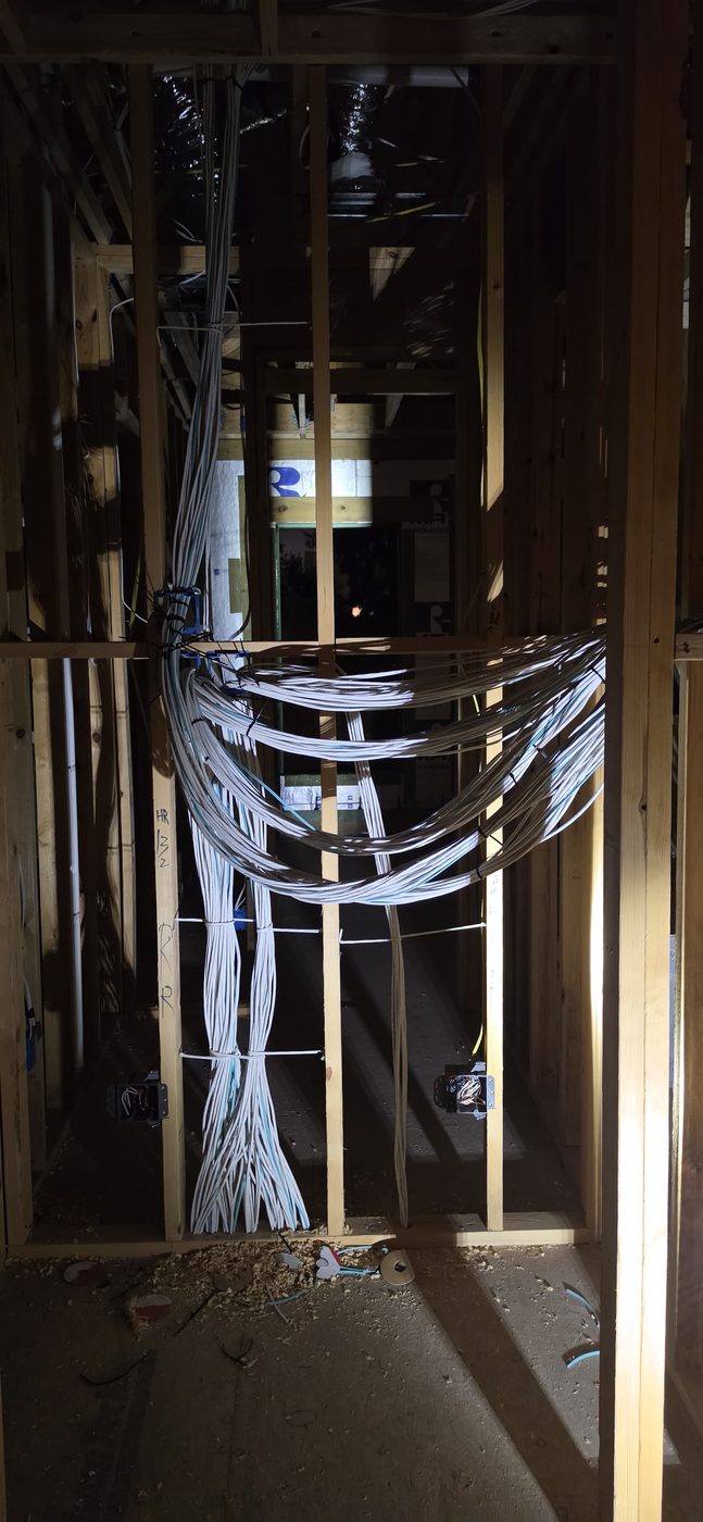 AV cabling routed through open studs to a planned equipment location before drywall