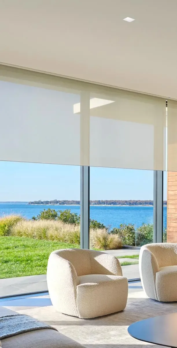 Modern living room with Lutron motorized shades, warm downlighting, and a waterfront view