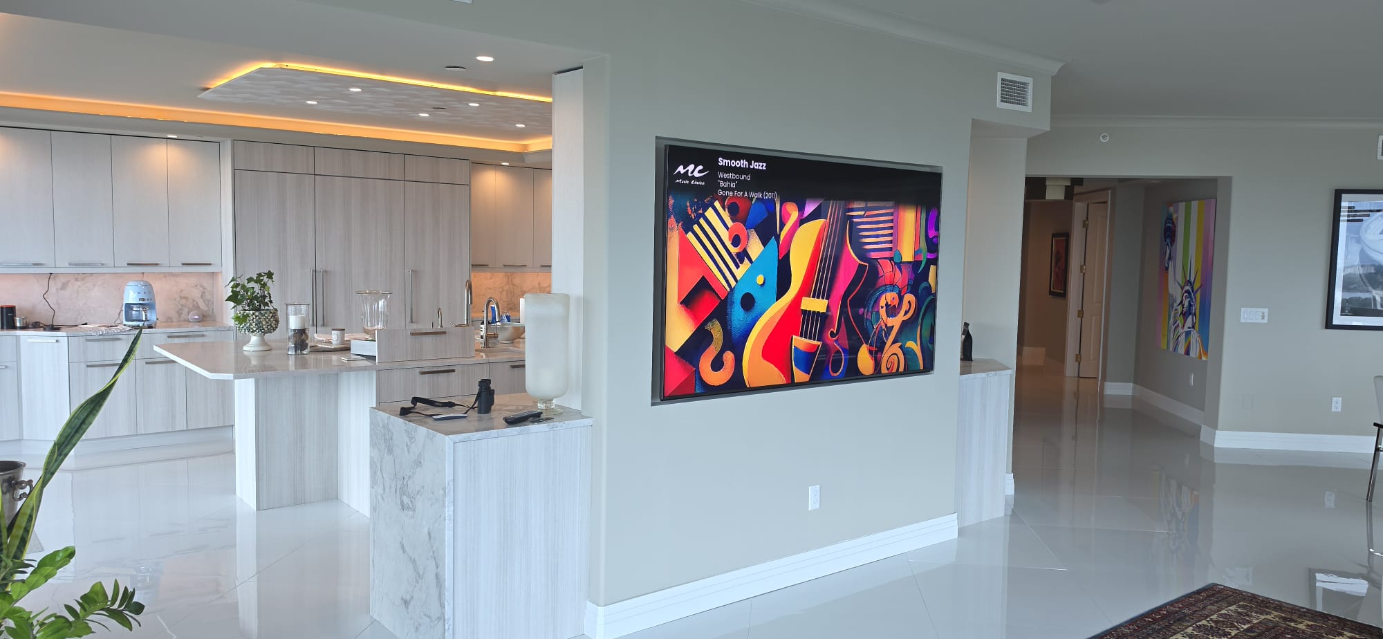 Luxury condo living room with wall-mounted TV and integrated surround sound system by Entertainment Pros