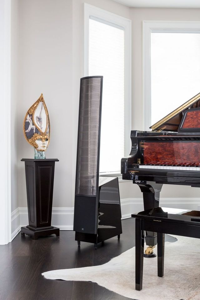 A slim MartinLogan ElectroMotion electrostatic speaker beside a grand piano