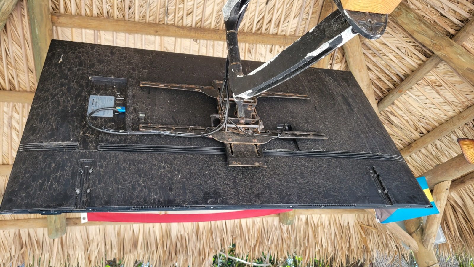 Back of an outdoor TV on an articulating mount during installation under a thatched tiki hut